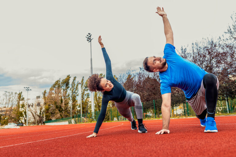 Smiling fitness couple stretching before morning workout on runn